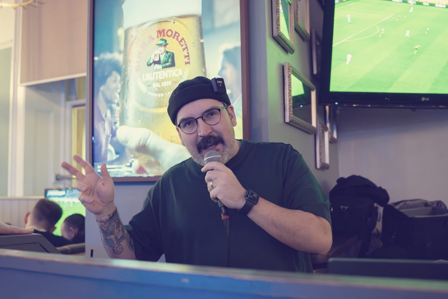 Gary hosting a quiz in a pub, microphone in hand, mid-question.